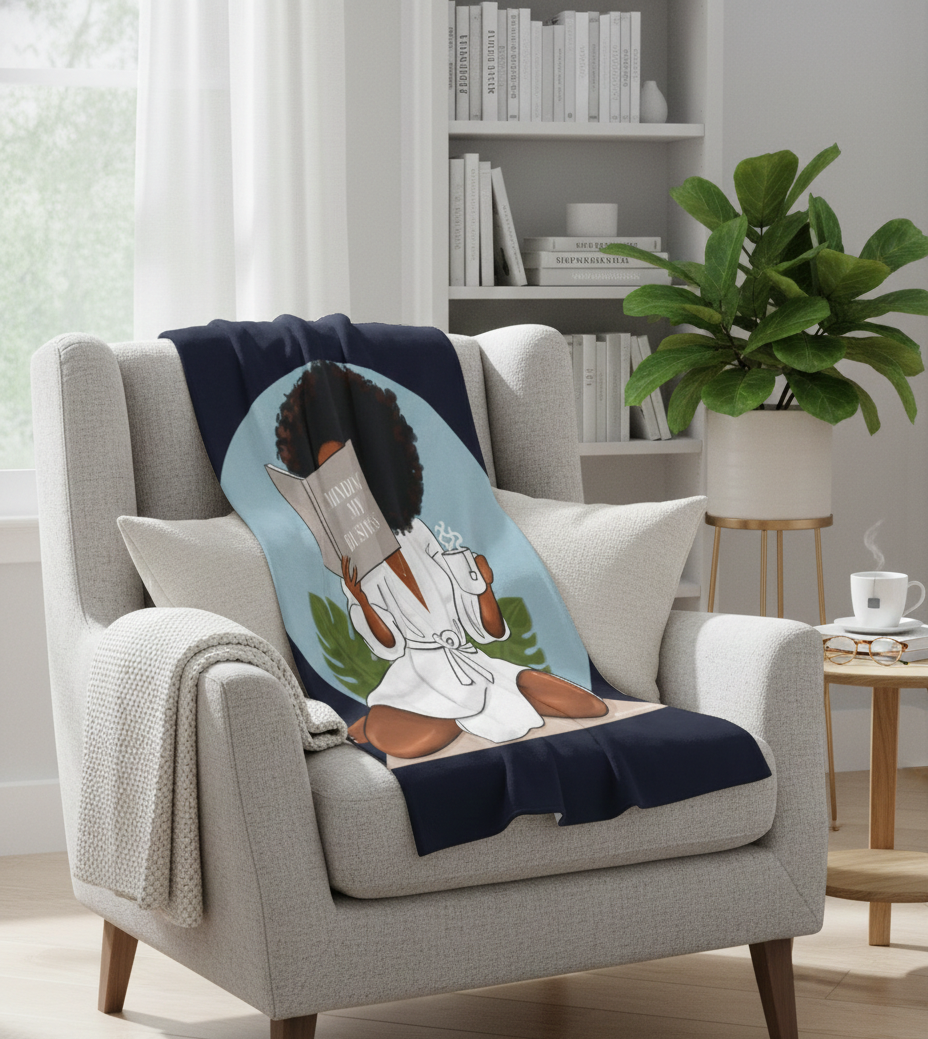 Blanket with a design of a person holding a book draped over a chair in a room with books and a plant.